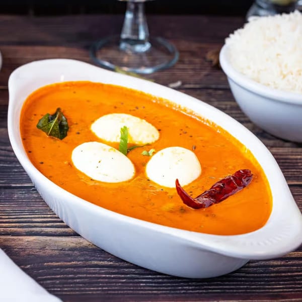 Amaravati Indian Cuisine's egg curry with three whole eggs in a rich orange sauce, garnished with chili and herbs.